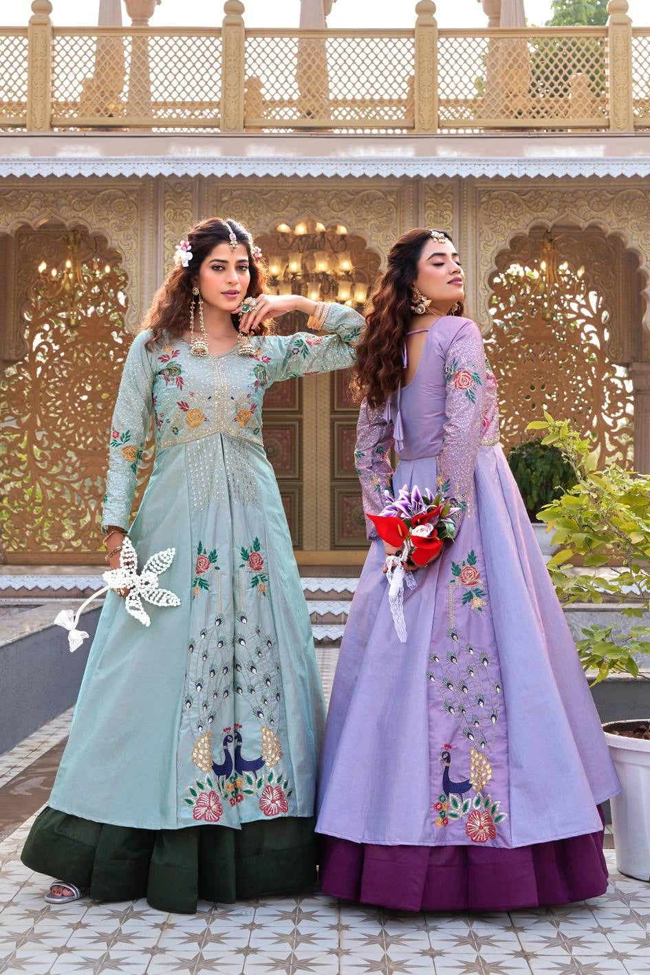 Two women in traditional embroidered dresses standing in front of a decorative building.